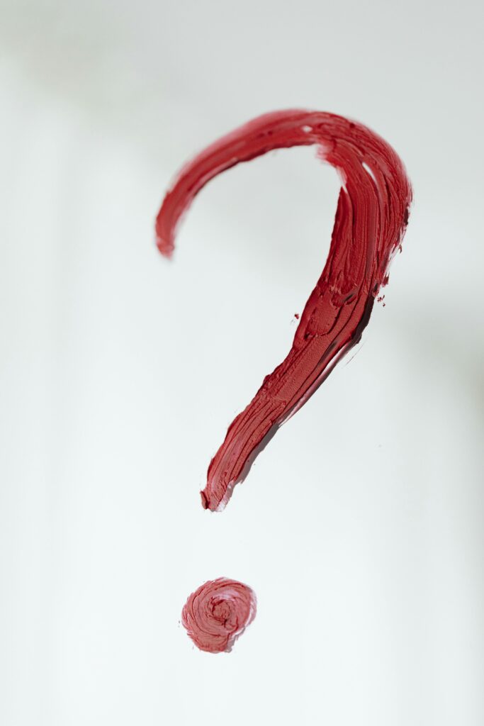 Close-up of a red painted question mark on a white background. Conceptual and abstract art.